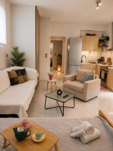 a living room with a white couch and a kitchen at S&M Cozy Garden Lagonissi in Lagonissi