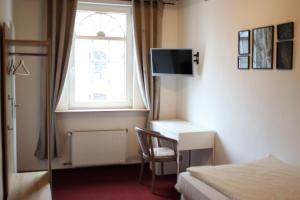 a bedroom with a bed and a desk and a window at Hotel Alt-Lennep in Remscheid