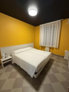 a bedroom with a white bed and a yellow wall at Appartamento Centro Direzionale Cerea in Cerea