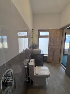 a bathroom with two sinks and a toilet and a door at Ostal Residency Pangong in Meruk