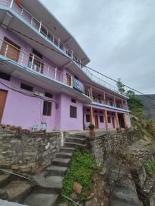ein rosafarbenes Gebäude mit einer Treppe davor in der Unterkunft Devom Guest House in Phata