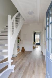 a white staircase in a white house with a blue door at Am Achterwasser DORF 12 in Rankwitz
