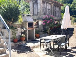 a table and chairs and an umbrella in front of a house at Casa da Laija - Vistas rio - "Gerês" in Geres