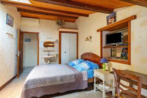 a bedroom with a bed and a tv on a wall at Chambre d'hôtes La Champagne in Sémussac