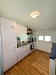 a kitchen with white cabinets and a wooden floor at Haus Bünten in Quinten