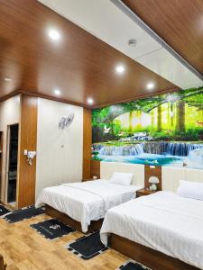 two beds in a room with a painting on the wall at Panda Hotel in Long Thành