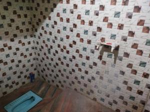 a bathroom with a tiled wall with a toilet at Jp Homestay in Vrindāvan