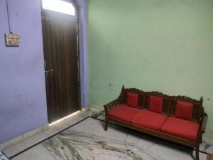 a red couch in a room with a door at Jp Homestay in Vrindāvan