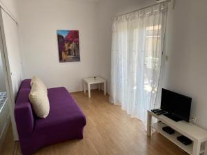 a living room with a purple couch and a tv at Apartments Olea in Rab