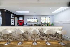 a bar with white stools in front of a counter at Hotel Miami Calella in Calella