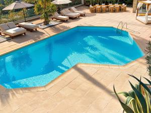 a large blue swimming pool with chairs and umbrellas at Sea View Villa Roc d'Azur - Pool - Jacuzzi in Vallauris