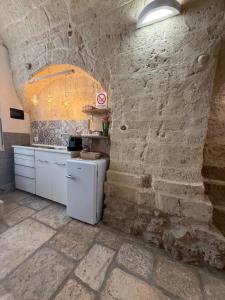 a kitchen with a stone wall and a white refrigerator at Agrimi b&b in Mesagne