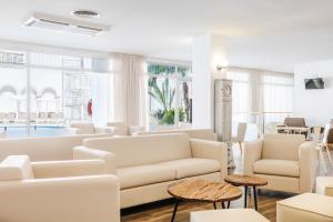a living room with white couches and tables and windows at Hotel Miami Calella in Calella