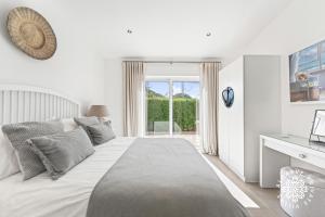 a white bedroom with a large bed and a window at Villa Benjamin - Vale do Lobo in Vale do Lobo