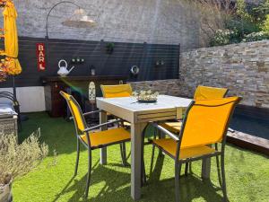 a table and chairs in a garden with a table and yellow chairs at Maison Paillette à Saint Saturnin in Saint-Saturnin-lès-Avignon