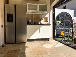 a kitchen with a stainless steel refrigerator and a window at Maison Paillette à Saint Saturnin in Saint-Saturnin-lès-Avignon