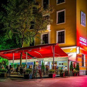 a restaurant with a red umbrella in front of a building at Corner Hotel & Kávéház in Dunaújváros