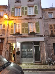 a building with green shuttered windows on a street at Irie Vibes in Bourganeuf