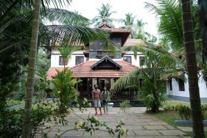 two people standing in front of a house at Poomuttathillam in Kunnamangalam