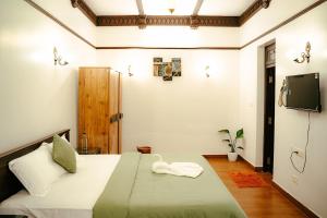 a bedroom with a bed and a tv on the wall at Poomuttathillam in Kunnamangalam +4 photos