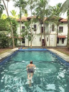 a man in a swimming pool in front of a house at Poomuttathillam in Kunnamangalam