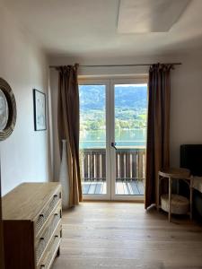 a bedroom with a large window with a view of a balcony at Chic & Cozy Lake View Apartment in Seeboden