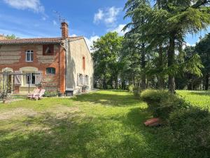 an old brick house with a grass yard at Hébergement TRAVAILLEURS in Monestrol