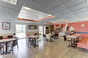 a dining room with tables and chairs in a restaurant at Ace Hotel Montluçon in Saint-Victor