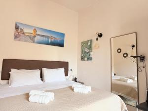 a bedroom with a bed with white sheets and a mirror at Guesthouse Historical Palacinho de São Antonio in Birgu