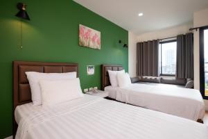 two beds in a room with green walls at โรงแรมต้นเงิน in Khon Kaen