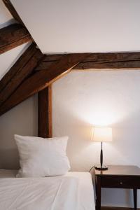 a bed with a white pillow and a table with a lamp at Schloss Maierhofen in Painten