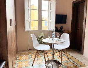 a table with two chairs and wine glasses on it at Guesthouse Historical Palacinho de São Antonio in Birgu