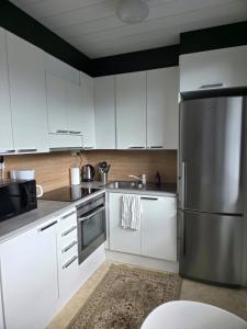 a kitchen with white cabinets and a stainless steel refrigerator at Kotoisa 1 in Seinäjoki