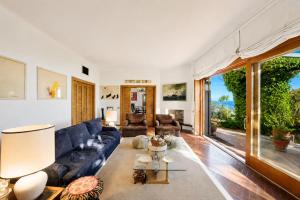 a living room with a blue couch and a large window at Hostdomus - Villa Gabriella with private pool in Alassio