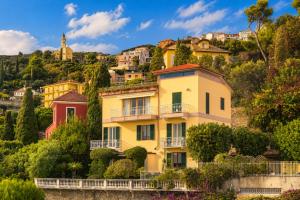 a yellow house on the side of a hill at Hostdomus - Villa Gabriella with private pool in Alassio