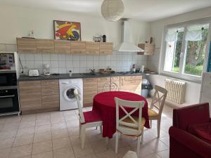 a kitchen with a table and a washing machine at Hébergement TRAVAILLEURS in Monestrol