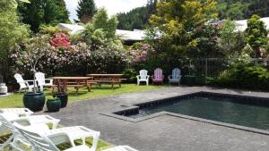 a backyard with a pool and chairs and a picnic table at Central Park Motor Inn in Taumarunui