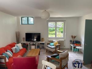 a living room with a red couch and a tv at Hébergement TRAVAILLEURS in Monestrol