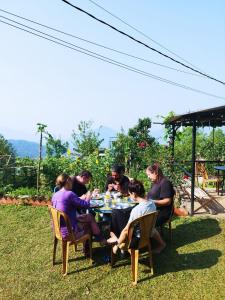a group of people sitting around a table in the grass at Mountain View Eco Farm in Rānīpauwa