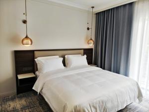 a bedroom with a large white bed with two pillows at Central Park Hotel 中央公园酒店 in Jalal-Abad +86 photos
