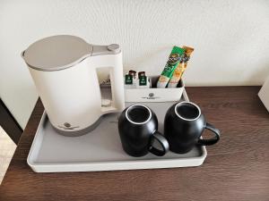 a coffee maker and two mugs on a tray at Central Park Hotel 中央公园酒店 in Jalal-Abad