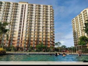 a swimming pool in front of a large building at Studio Type Furnished Condo in Lapu Lapu City