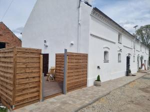 a white building with a wooden fence next to it at Biały Zakątek in Trzebnica