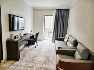 a hotel room with a couch and a desk and a television at Central Park Hotel 中央公园酒店 in Jalal-Abad