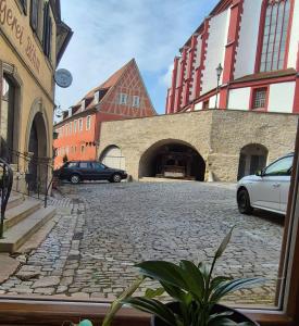 a cobblestone street with two cars parked in front of buildings at Ferienwohnung 1890 in Dettelbach