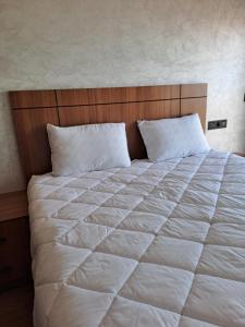 a large white bed with a wooden head board at Blue Horizon Mansouriah in Mohammedia