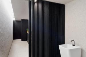 a bathroom with a white sink and a black wall at Alpine Contrapposto in Solčava +24 photos