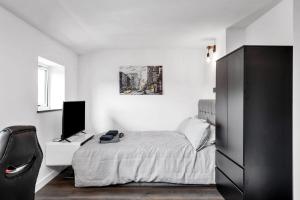 a bedroom with a bed and a desk with a television at Modern Cambridge Studio in Milton