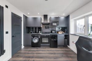 a kitchen with gray cabinets and a washer and dryer at Modern Cambridge Studio in Milton