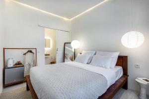 a bedroom with a large white bed and a mirror at Pyramid Ateliero Hotel Canggu in Canggu